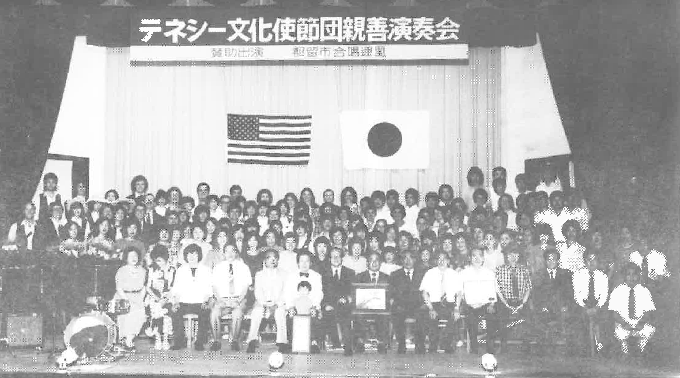A large group of Hendersonville and Tsuru residents sit together on a stage